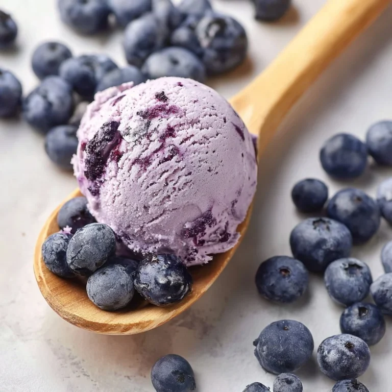 A bowl of creamy homemade no churn blueberry ice cream with fresh blueberries on top.
